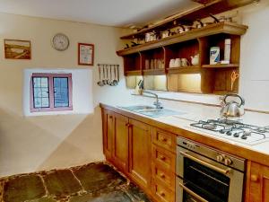a kitchen with a sink and a stove at Longhouse - Y Beudy in Rhayader +2 photos