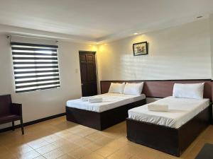 a bedroom with two beds and a chair and a window at Tagaytay Haven Hotel in Tagaytay