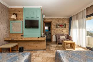 a hotel room with a bed and a television at Assos Dove Hotel Resort & SPA in Behramkale