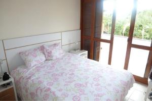 1 dormitorio con 1 cama con manta rosa y almohadas en Triplex/ Cabana 08, en Florianópolis