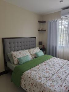 a bedroom with a bed with a green comforter and a window at Villa Bosque - Forest Residences in Antipolo