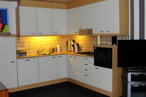 una cucina con armadietti bianchi e forno a microonde di Herkenhoek 3 bedroom apartement a Heeswijk-Dinther