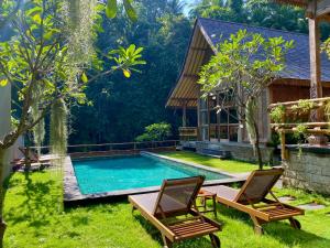 a pool in a yard with two chairs and a house at The Villa Lululu in Tabanan