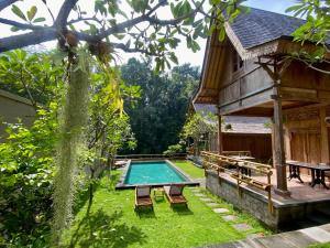 a swimming pool in a yard next to a house at The Villa Lululu in Tabanan