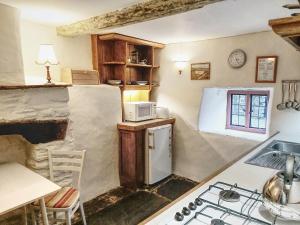 a kitchen with a refrigerator and a stove top oven at Longhouse - Y Beudy in Rhayader