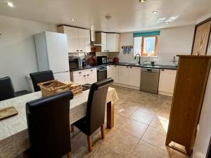 a kitchen with a table and chairs and a kitchen with white cabinets at Millers Cottage in Llandysul