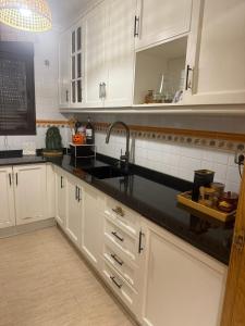 a kitchen with white cabinets and a black counter top at Playa y Geoda, escapada perfecta in Pilar de Jaravía