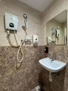 a shower in a bathroom with a sink and a mirror at Q Inn by Pillow Plus in Petaling Jaya