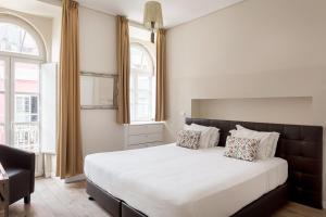 a bedroom with a large bed and two windows at Suites Guest House in Cascais