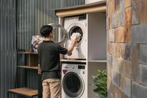a man standing in front of a washing machine at Modapick Bạch Đằng - Living in the nature garden with full river view in Hanoi