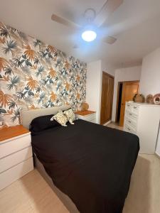a bedroom with a large black bed with a wall at Playa y Geoda, escapada perfecta in Pilar de Jaravía