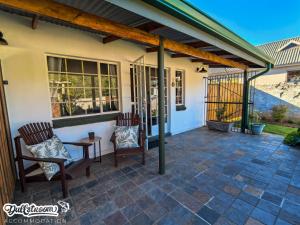 a patio with two chairs and a wooden pergola at Suikerbosch Room 1 and Room 2 in Dullstroom +19 photos
