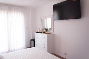 a bedroom with a bed and a mirror and a dresser at Hostal Comercio in Denia +15 photos