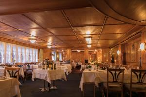 a restaurant with white tables and chairs and windows at Hotel Säntis - Genuss & Tradition in Appenzell