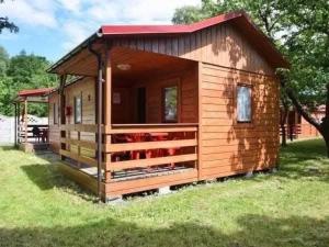 a small wooden cabin with a red roof at Domki Mucki in Międzywodzie