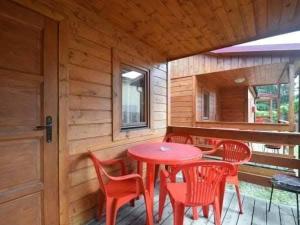 a small red table and chairs on a porch at Domki Mucki in Międzywodzie