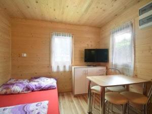 a room with a bed and a table in a cabin at Domki Mucki in Międzywodzie