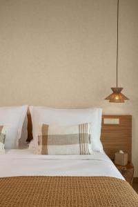 a bedroom with a bed with white sheets and pillows at Legacy Ithos Boutique Hotel in Porto Santo