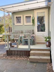 a small house with a porch and a bench on the porch at Knus Tiny house 2 pers rust natuur en privacy in Borger