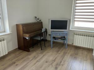 a room with a piano and a desk with a television at Apartament z pianinem in Grajewo