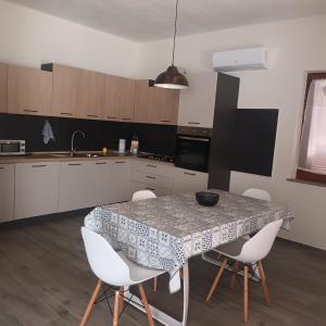 a kitchen with a table and some white chairs at Valentina's garden house in Triei