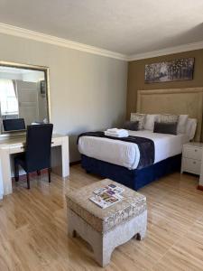 a hotel room with a bed and a desk and a bed sidx sidx sidx sidx at The Palms Bed & Breakfast in Bizana +8 photos