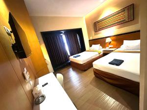 a hotel room with two beds and a desk at Hotel De Green Lampung in Lampung +4 photos