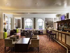 a bar in a hotel with tables and chairs at Mercure Aberdeen Caledonian Hotel in Aberdeen