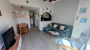 a living room with a blue couch and a table at Paradise COSTA ARENAL in Es Mercadal