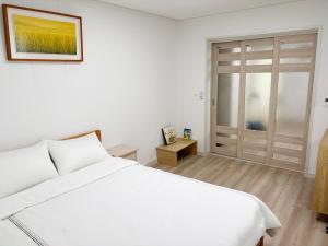 a white bedroom with a white bed and a door at 깨비하우스201 in Wŏlsan