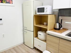 a kitchen with a white refrigerator and a microwave at 깨비하우스201 in Wŏlsan