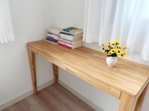 a wooden table with a vase of flowers and books at 깨비하우스201 in Wŏlsan