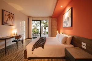 a hotel room with a bed and a desk and a window at Modapick Bạch Đằng - Living in the nature garden with full river view in Hanoi