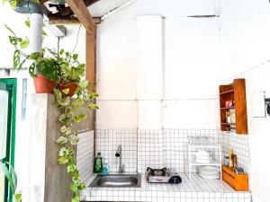 a white tiled bathroom with a sink and a toilet at ŚamaStay in Yogyakarta