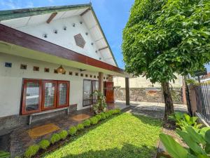 a house with a tree in front of it at ŚamaStay in Yogyakarta