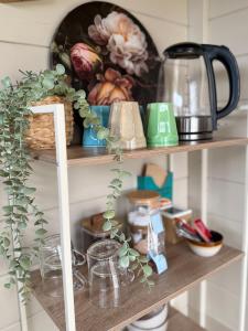 a shelf with dishes and other items on it at Knus Tiny house 2 pers rust natuur en privacy in Borger