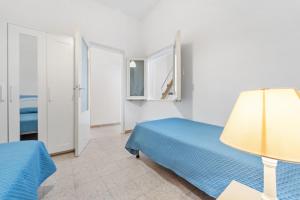 a bedroom with a blue bed and a lamp at Al centro del Borgo in Calasetta