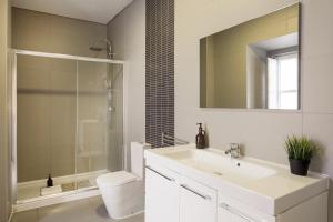 a bathroom with a sink and a toilet and a mirror at Suites Guest House in Cascais