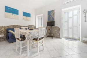a white dining room with a table and chairs at Al centro del Borgo in Calasetta +17 photos