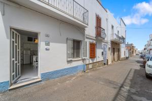 a white building with an open door on a street at Al centro del Borgo in Calasetta