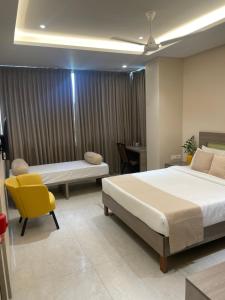 a bedroom with two beds and a yellow chair at Raghav Residency in Vellore