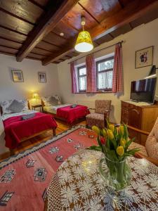 a room with two beds and a table with a vase of flowers at Alsópetényi Vendégházak in Alsópetény