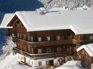 un gran edificio de madera con nieve en el techo en Bergbauernhof Ausserberglet en Innervillgraten