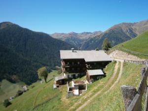 un edificio en una colina con montañas en el fondo en Bergbauernhof Ausserberglet en Innervillgraten