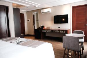 a hotel room with a bed and a table and a tv at Radiant Hotel and Events in San Fernando