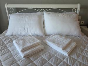 a white bed with white pillows and towels on it at Ippokratis 1 in Larisa