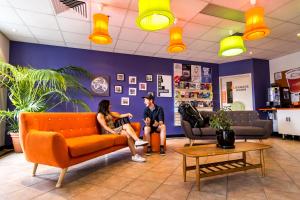 two people sitting on a couch in a waiting room at YHA Adelaide Central in Adelaide