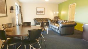 sala de estar con sofá, mesa y sillas en Randolph Motel Apartments en Christchurch