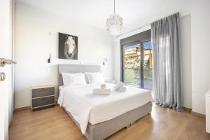 a white bedroom with a large bed and a window at Athenean Oasis in Ellinikon in Athens