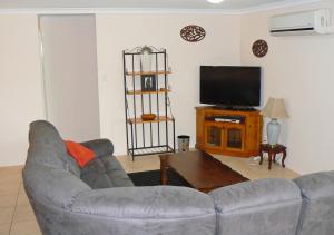 Geraldton Luxury Vacation Home with free Streaming في جيرالدتون: غرفة معيشة مع أريكة وتلفزيون بشاشة مسطحة